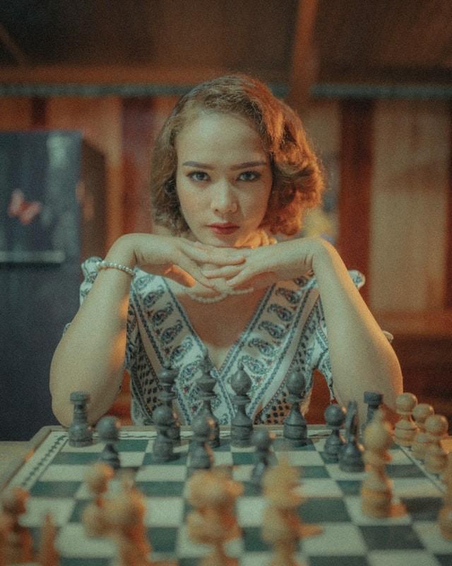 Meisje met rood haar achter een schaakbord.